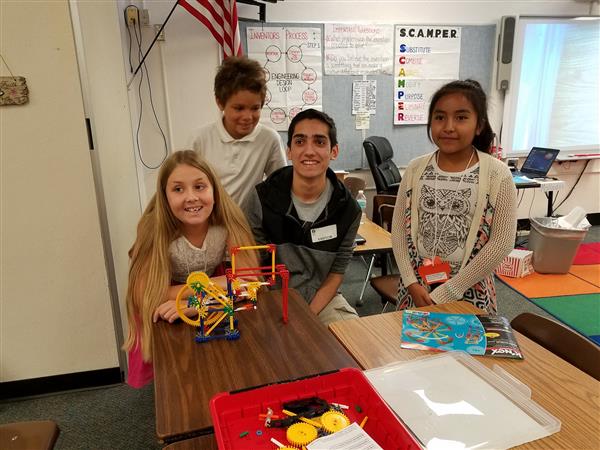 High school student helping elementary students with science project High school student helping elementary students with science project